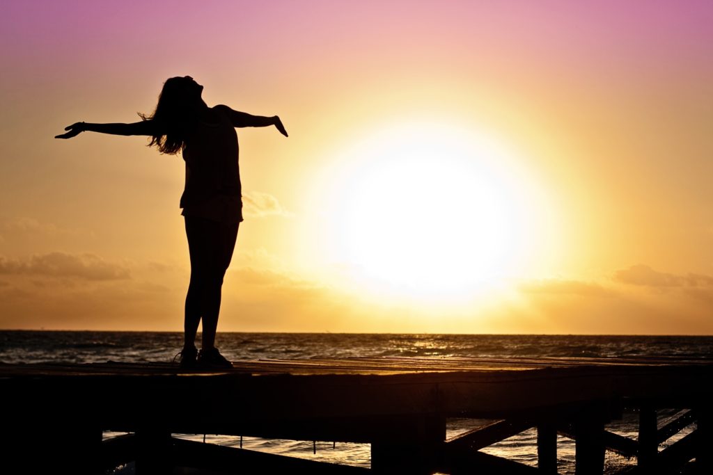 photo of woman arms wide open in sunset