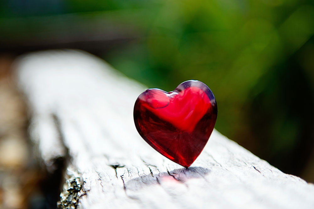 photo of red heart jewel on a log