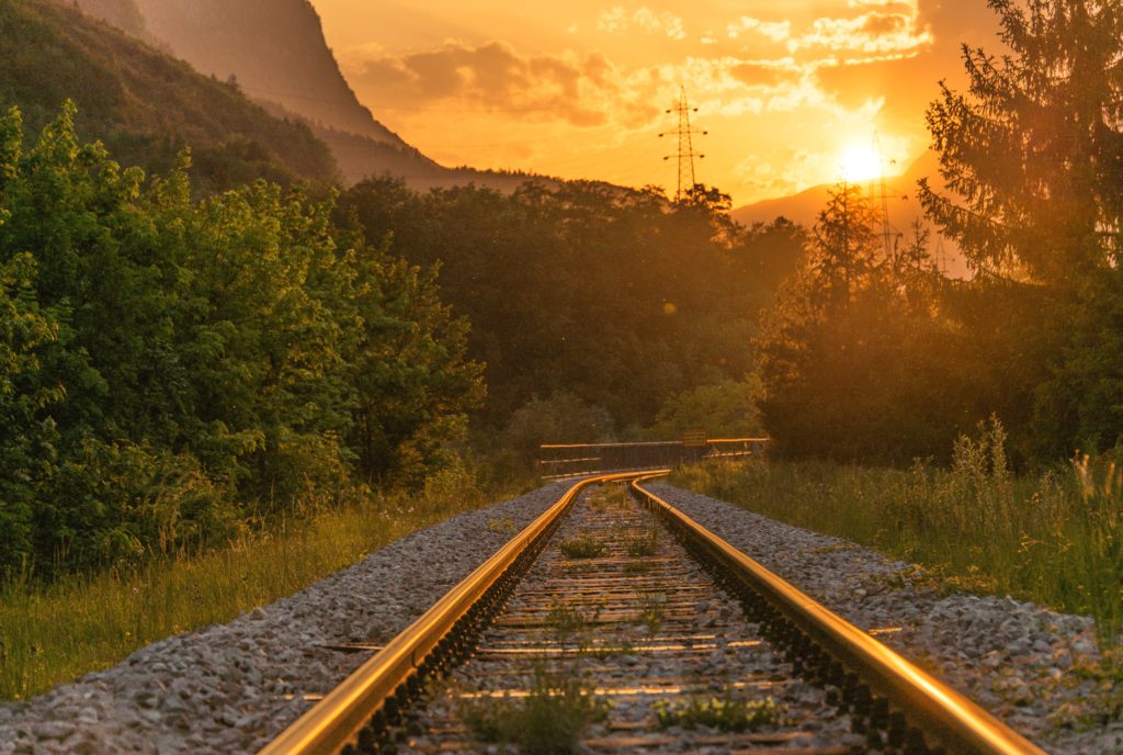 photo of train tracks leading into sunset