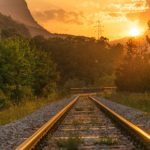 photo of train tracks leading into sunset
